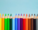 pencil crayons lined up like a rainbow on a sky-blue background